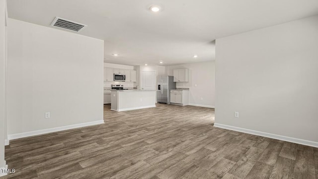 unfurnished living room featuring visible vents, recessed lighting, baseboards, and wood finished floors