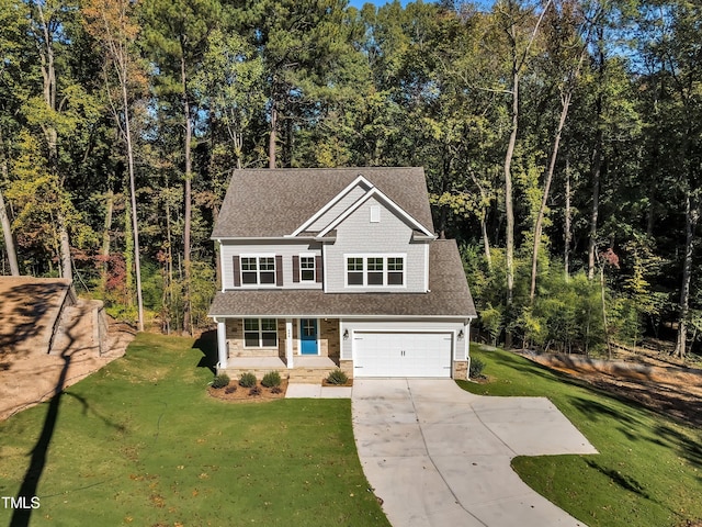 traditional-style house with covered porch, roof with shingles, an attached garage, concrete driveway, and a front lawn