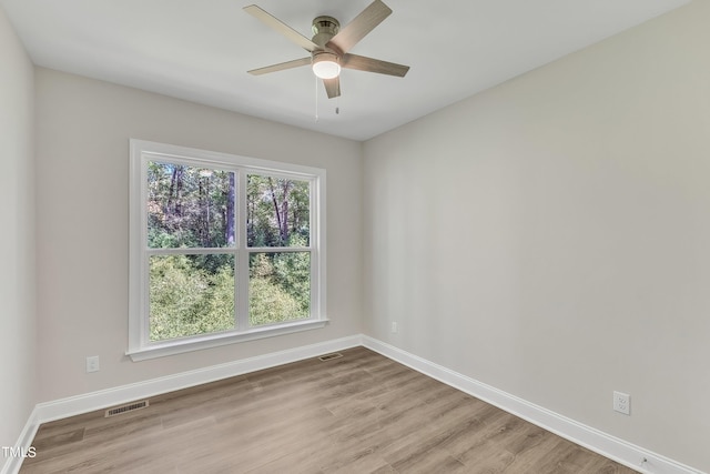 unfurnished room featuring baseboards, visible vents, a ceiling fan, and wood finished floors