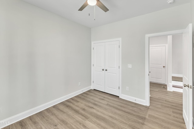 unfurnished bedroom with baseboards, light wood-style floors, a closet, and a ceiling fan