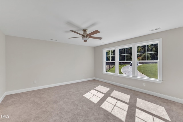 unfurnished room with light colored carpet, baseboards, a ceiling fan, and visible vents