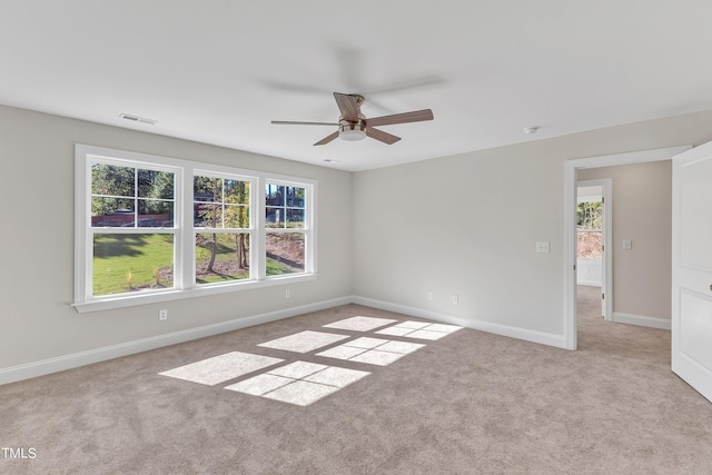 unfurnished room with baseboards, ceiling fan, visible vents, and a wealth of natural light