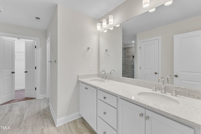 bathroom with double vanity, baseboards, a shower stall, and a sink