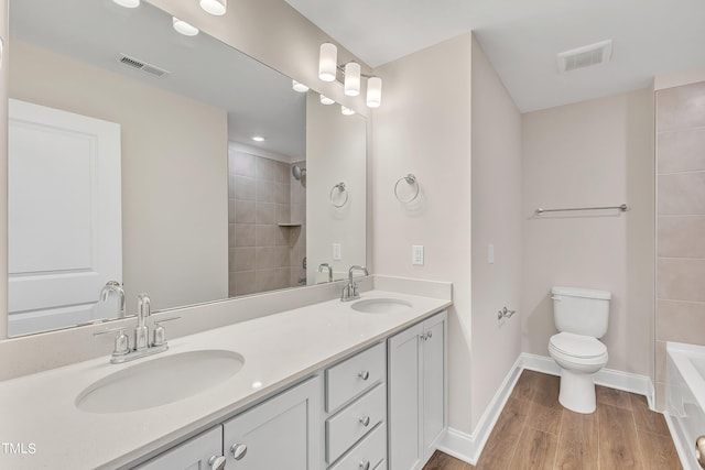 full bathroom with tiled shower / bath, vanity, hardwood / wood-style flooring, and toilet