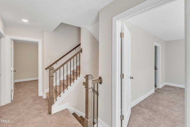 hallway featuring carpet, baseboards, and an upstairs landing
