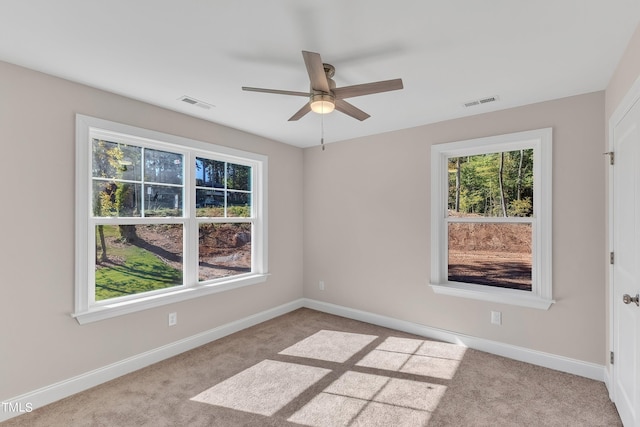 carpeted spare room with visible vents, baseboards, and a ceiling fan