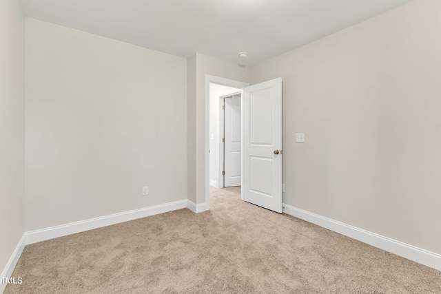 spare room with light colored carpet and baseboards