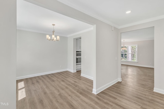 empty room featuring an inviting chandelier, crown molding, and light wood-type flooring