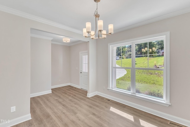 spare room with light hardwood / wood-style floors, ornamental molding, and an inviting chandelier