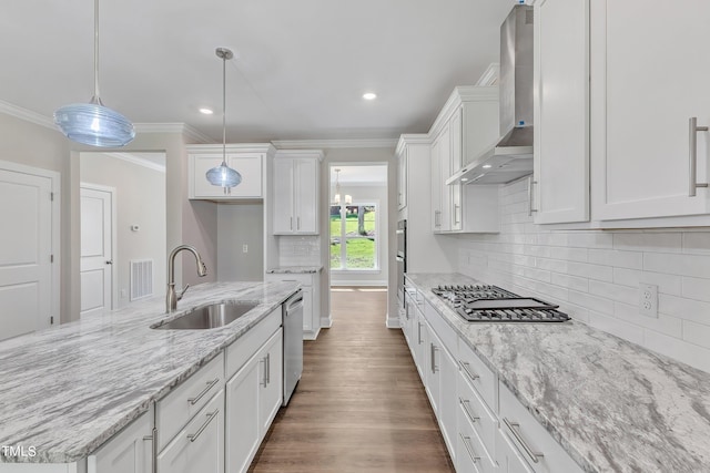 kitchen with a sink, crown molding, visible vents, wall chimney range hood, and appliances with stainless steel finishes