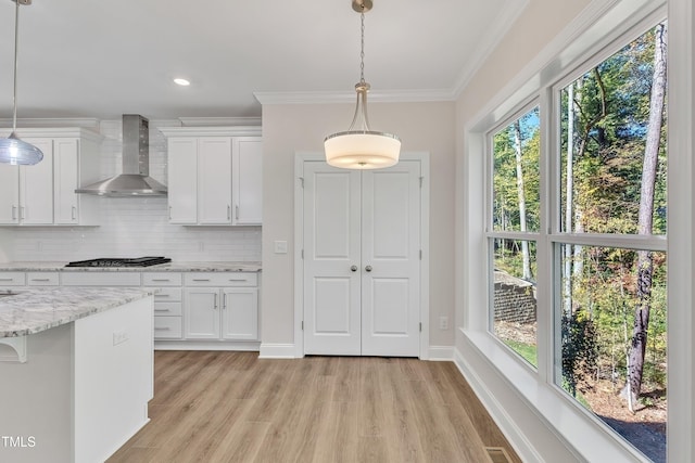 kitchen featuring wall chimney exhaust hood, white cabinetry, and plenty of natural light