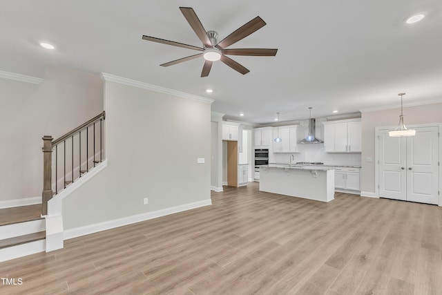 unfurnished living room with ornamental molding, sink, light wood-type flooring, and ceiling fan