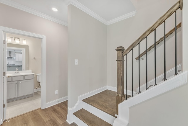 stairs with ornamental molding, sink, and hardwood / wood-style flooring