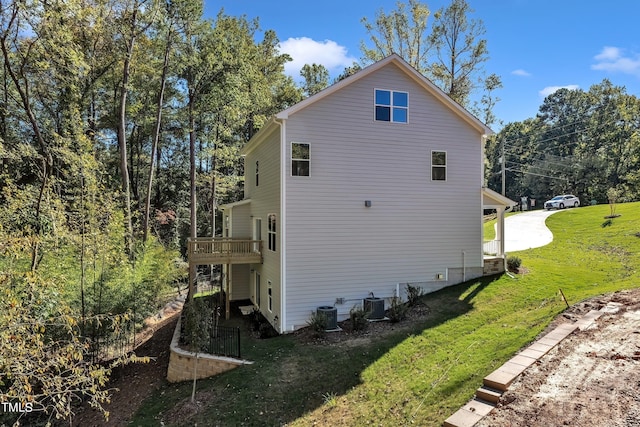 view of side of home featuring central AC unit, a wooden deck, and a lawn