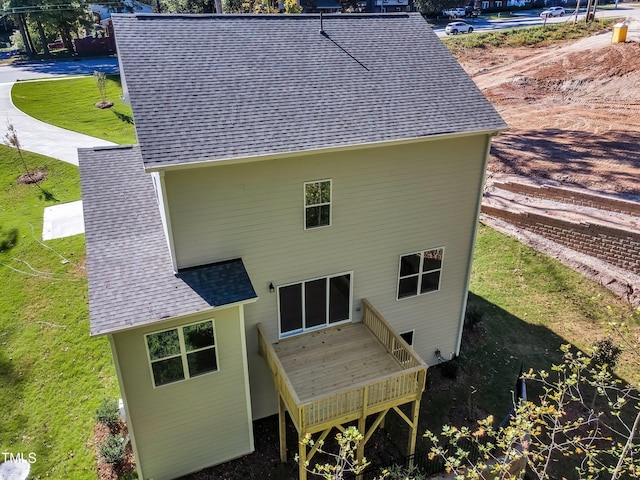 rear view of house featuring a lawn, roof with shingles, and a wooden deck