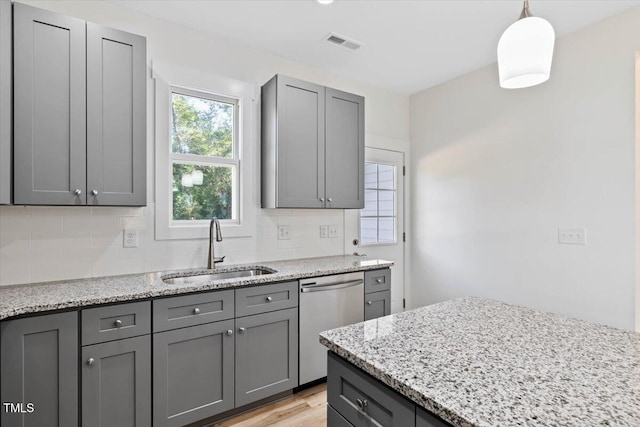 kitchen featuring backsplash, stainless steel dishwasher, pendant lighting, gray cabinetry, and sink