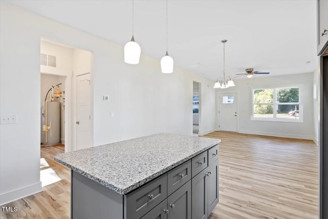 kitchen with water heater, gray cabinetry, a center island, decorative light fixtures, and light wood-type flooring