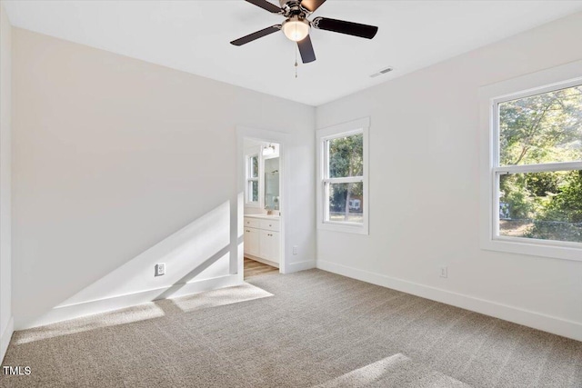 empty room with ceiling fan, light colored carpet, and plenty of natural light