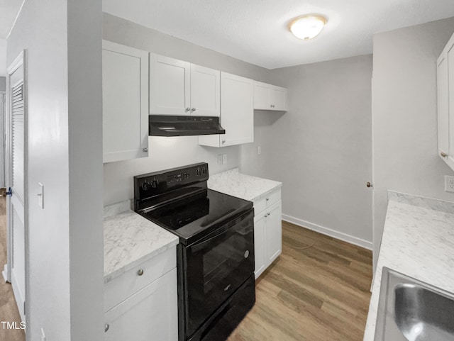 kitchen featuring black / electric stove, white cabinetry, light hardwood / wood-style floors, and light stone counters