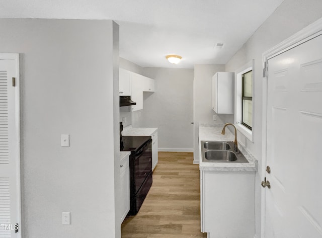 kitchen featuring sink, black / electric stove, light hardwood / wood-style flooring, and white cabinets