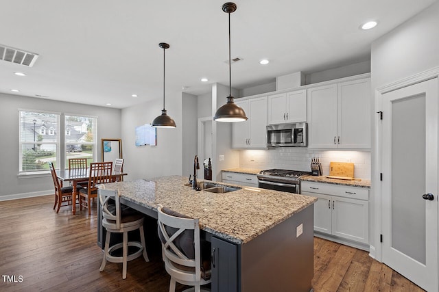 kitchen with a kitchen island with sink, appliances with stainless steel finishes, white cabinetry, and sink