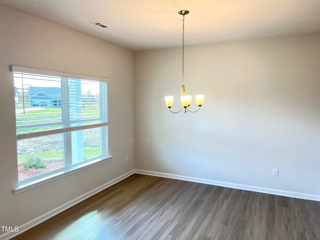 unfurnished room featuring a chandelier, dark wood-style flooring, and baseboards