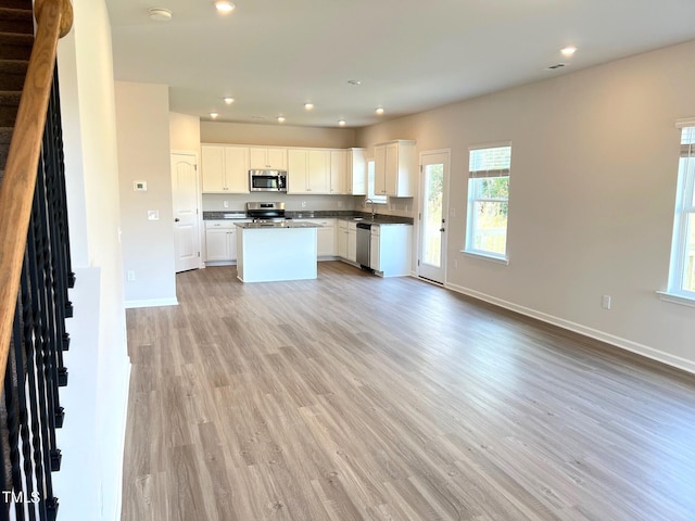 kitchen with stainless steel appliances, baseboards, light wood-style flooring, recessed lighting, and dark countertops