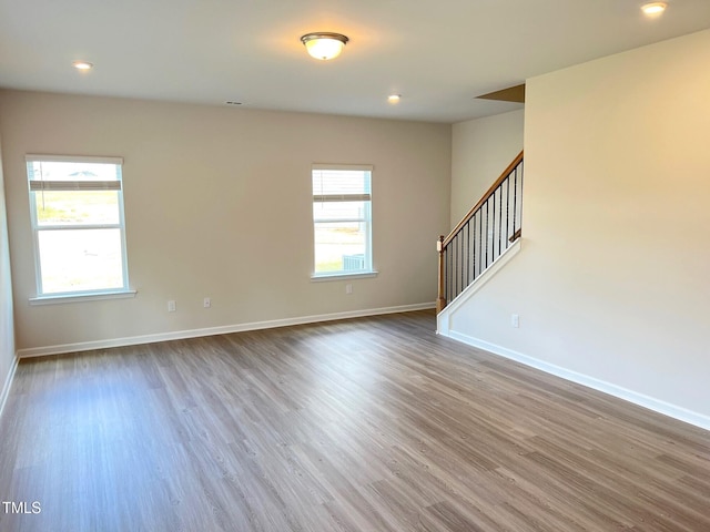 unfurnished living room featuring stairway, wood finished floors, baseboards, and recessed lighting