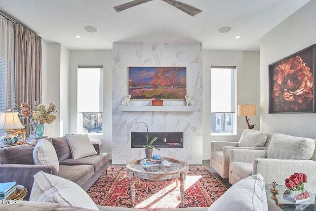 living room with a wealth of natural light, a premium fireplace, and ceiling fan