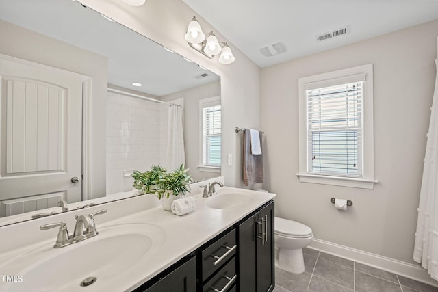 bathroom featuring vanity, tile patterned flooring, toilet, and a wealth of natural light