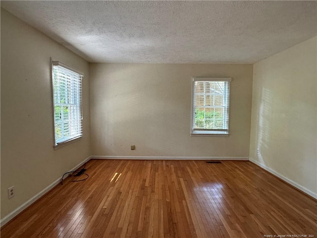 unfurnished room with a textured ceiling and light hardwood / wood-style floors