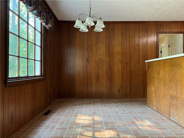 unfurnished dining area with a chandelier and wooden walls