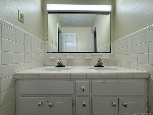 bathroom with tile walls, vanity, and a textured ceiling