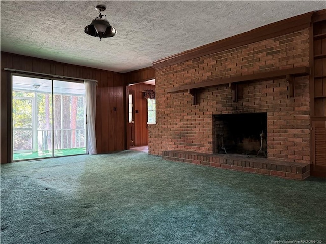 unfurnished living room featuring a brick fireplace, carpet flooring, wood walls, and a textured ceiling