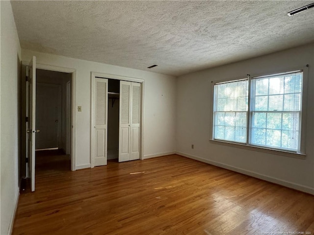 unfurnished bedroom featuring a closet, wood-type flooring, and a textured ceiling