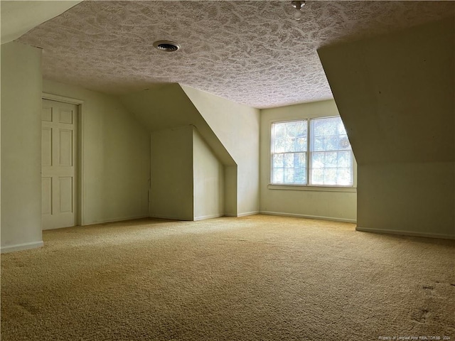 additional living space featuring light carpet and a textured ceiling