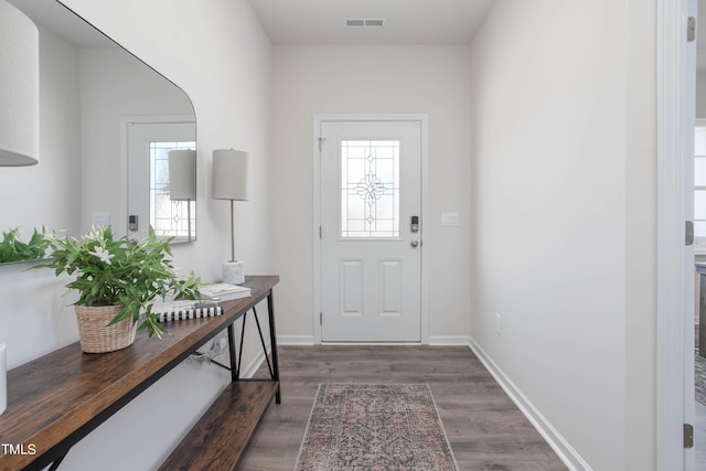 doorway to outside with baseboards, visible vents, and wood finished floors