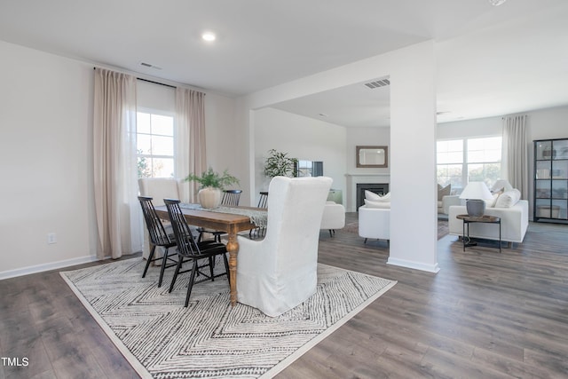 dining space with baseboards, a fireplace, visible vents, and wood finished floors