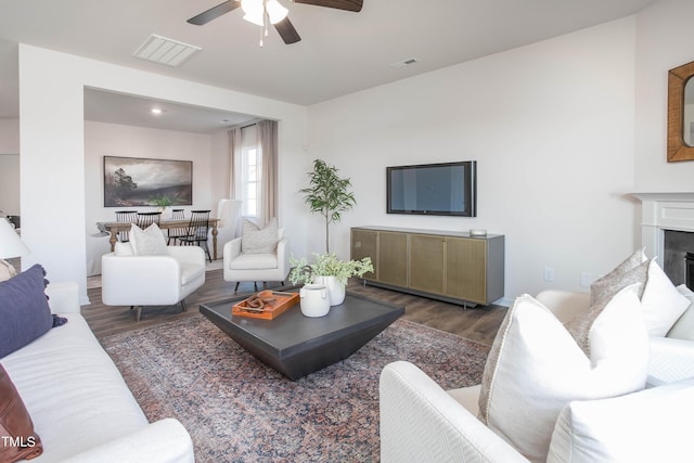 living room with a premium fireplace, visible vents, and wood finished floors