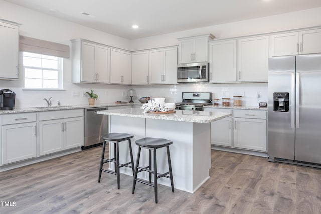 kitchen featuring a center island, a breakfast bar, stainless steel appliances, backsplash, and wood finished floors