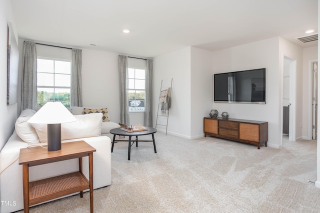 living room with visible vents, plenty of natural light, light carpet, and baseboards