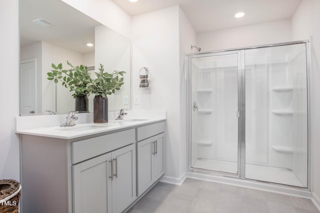 bathroom with double vanity, a stall shower, a sink, and recessed lighting