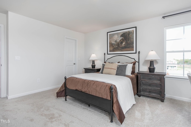 bedroom featuring light colored carpet, baseboards, and multiple windows