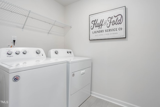 washroom with laundry area, washing machine and dryer, and baseboards