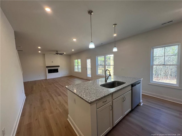 kitchen featuring sink, dishwasher, white cabinetry, hanging light fixtures, and light stone counters