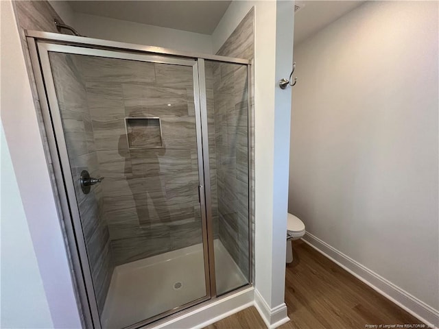 bathroom with hardwood / wood-style floors, toilet, and walk in shower