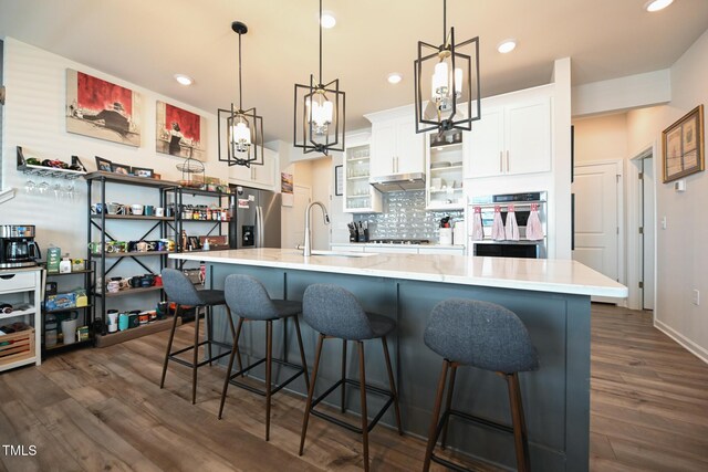 kitchen featuring dark hardwood / wood-style floors, tasteful backsplash, a breakfast bar, white cabinetry, and stainless steel appliances