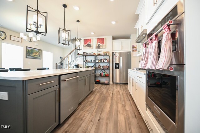 kitchen featuring stainless steel appliances, white cabinets, a center island, and gray cabinets