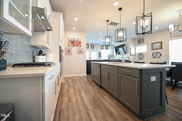 kitchen featuring dark hardwood / wood-style flooring, a kitchen island with sink, tasteful backsplash, pendant lighting, and white cabinets