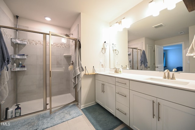 bathroom featuring double sink vanity, tile patterned floors, and a shower with shower door